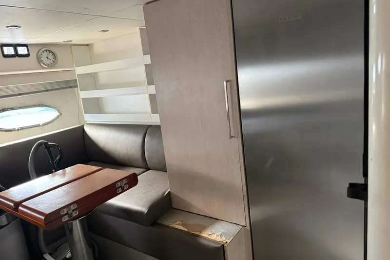  Yacht Photos Pics Interior of 2006 Sunseeker Predator 82 yacht with seating, table, and stainless steel fridge.