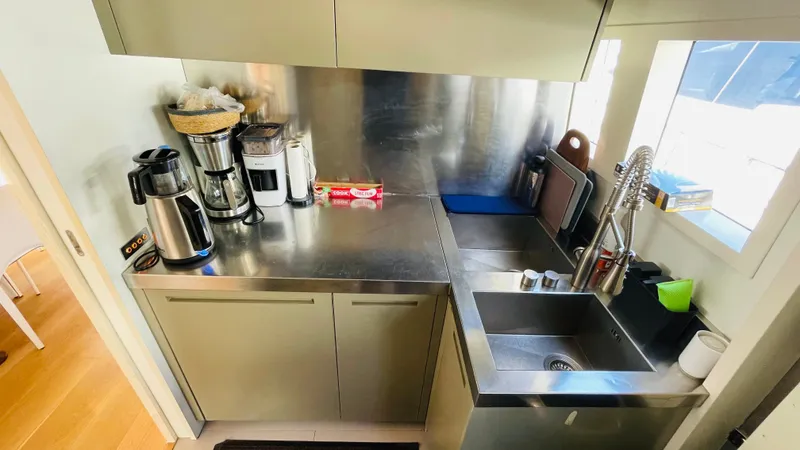  Yacht Photos Pics Compact stainless steel kitchen on a 2016 Canados 76 yacht, featuring modern appliances and sink.