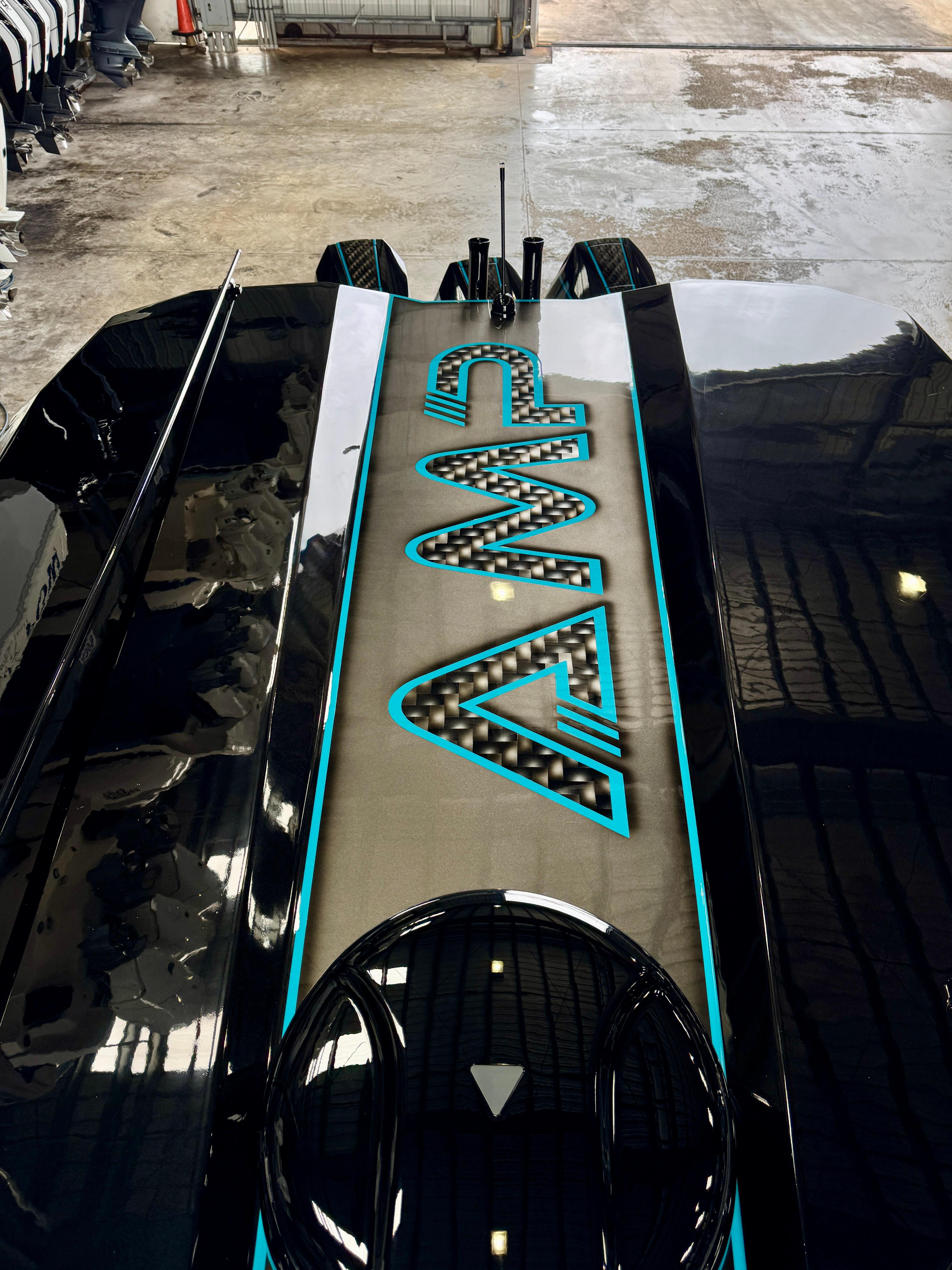 2024 AMP 333 vehicle with sleek black design and illuminated logo in a garage setting.