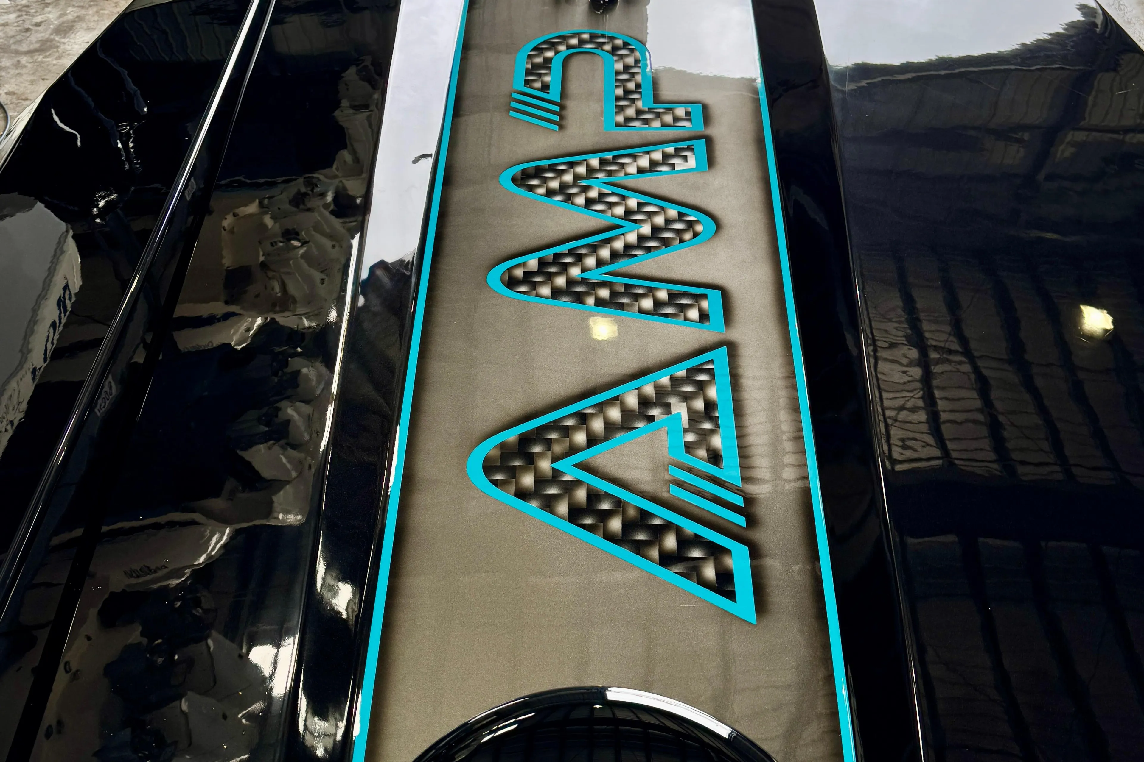 2024 AMP 333 vehicle with sleek black design and illuminated logo in a garage setting.