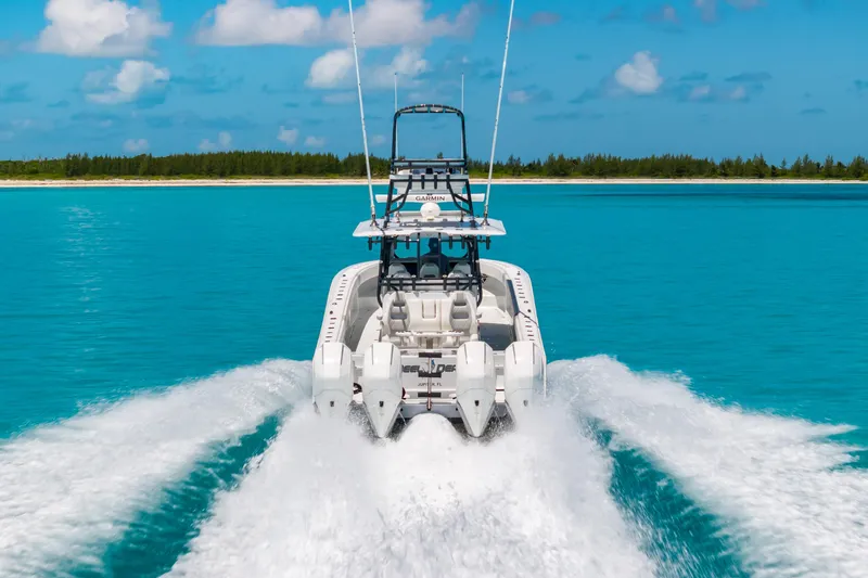 Reel Deal Yacht Photos Pics 2023 Freeman 42 LR boat cruising on turquoise water near a sandy shoreline.