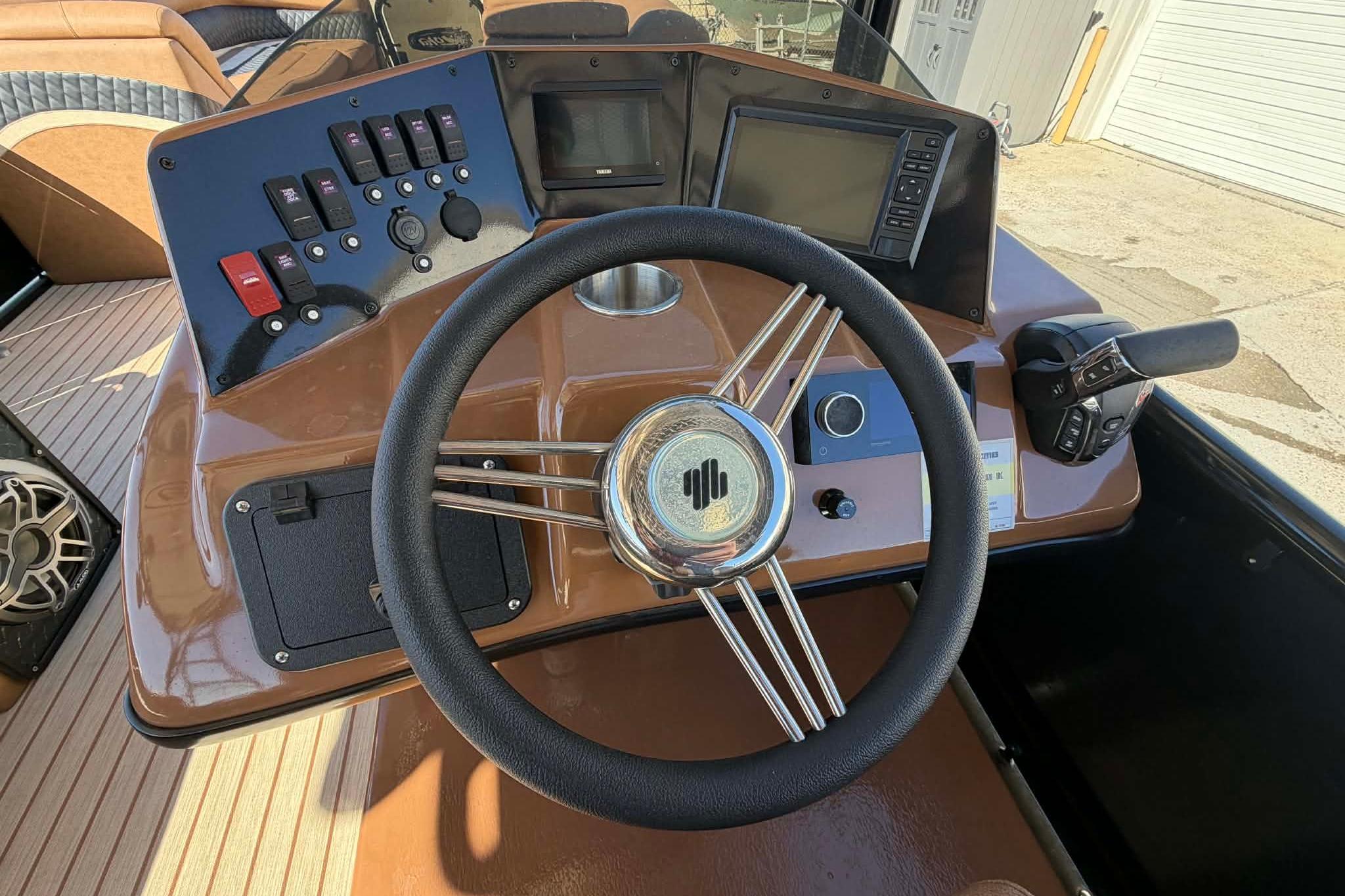 Steering console of 2026 Aloha Paradise 300 Sundeck with controls and display screens.