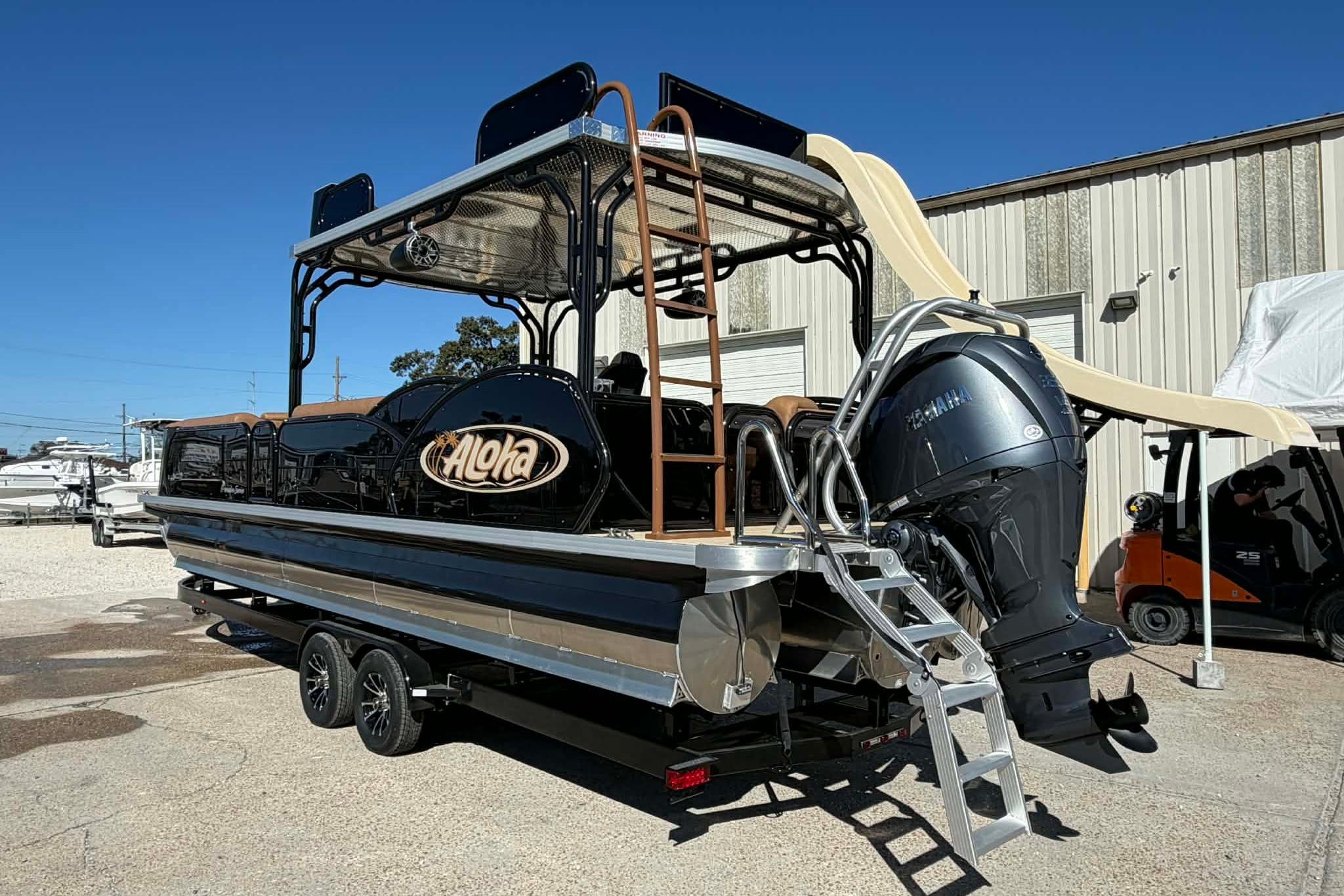 2026 Aloha Paradise 300 Sundeck boat with slide and Yamaha motor in a marina setting.
