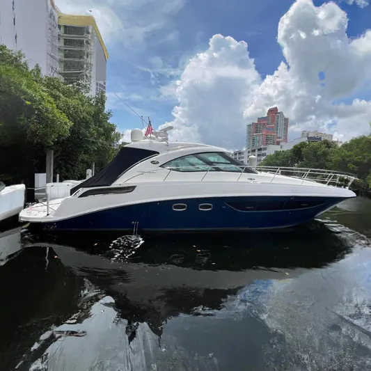 Moonwake Yacht Photos Pics 2014 Sea Ray 470 Sundancer yacht docked by lush greenery and urban skyline.