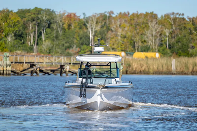  Yacht Photos Pics 2022 Axopar 37 Sun Top boat cruising on a calm river with forested background.