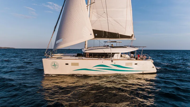  Yacht Photos Pics 2021 Lagoon 450 S catamaran sailing on open sea under clear blue sky.