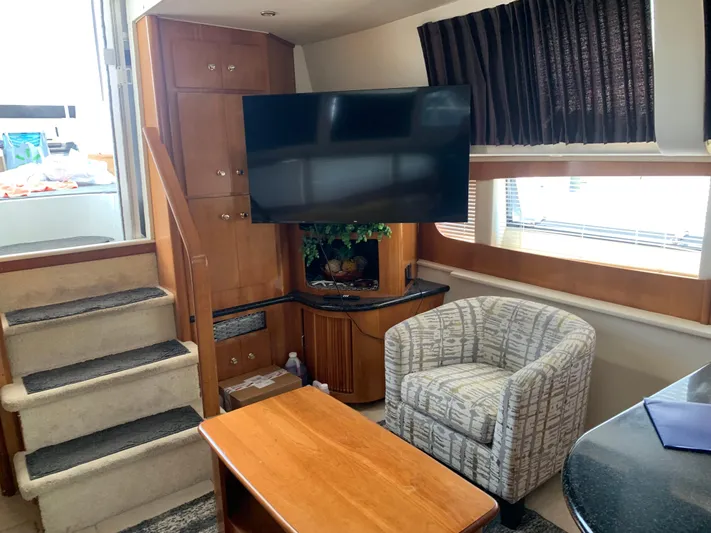 Busy Living Yacht Photos Pics Interior of 2001 Carver 396 Aft Cabin MY with TV, chair, and wooden cabinetry.