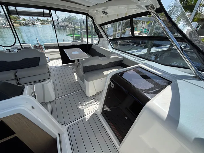 Namaste Yacht Photos Pics Interior of 2018 Aquila 36 Sport yacht with seating and table, docked by the water.