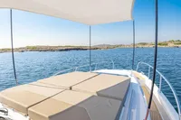 2023 Nimbus W11 boat with sunshade and cushioned deck, cruising on a clear blue sea.