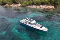 2023 Nimbus W11 boat cruising in clear turquoise waters near a lush, forested shoreline.