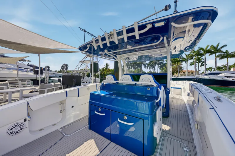  Yacht Photos Pics 2019 Midnight Express 43 Open yacht interior with blue console and seating, docked near palm trees.