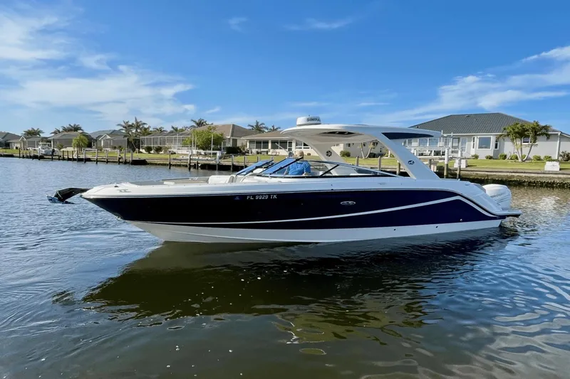  Yacht Photos Pics 2023 Sea Ray 310 SLX-OB boat on a calm waterway, with houses in the background.