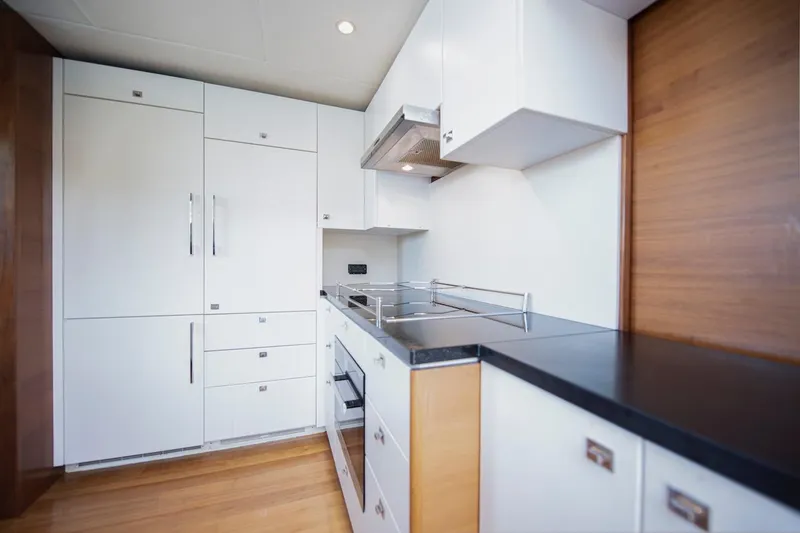 Lady Parisa Yacht Photos Pics Modern kitchen interior on 2014 Princess 88 Motor Yacht, featuring sleek white cabinetry.