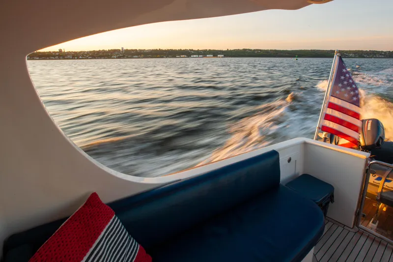  Yacht Photos Pics 2018 Hylas M44 yacht cruising at sunset with American flag, featuring a cozy seating area.