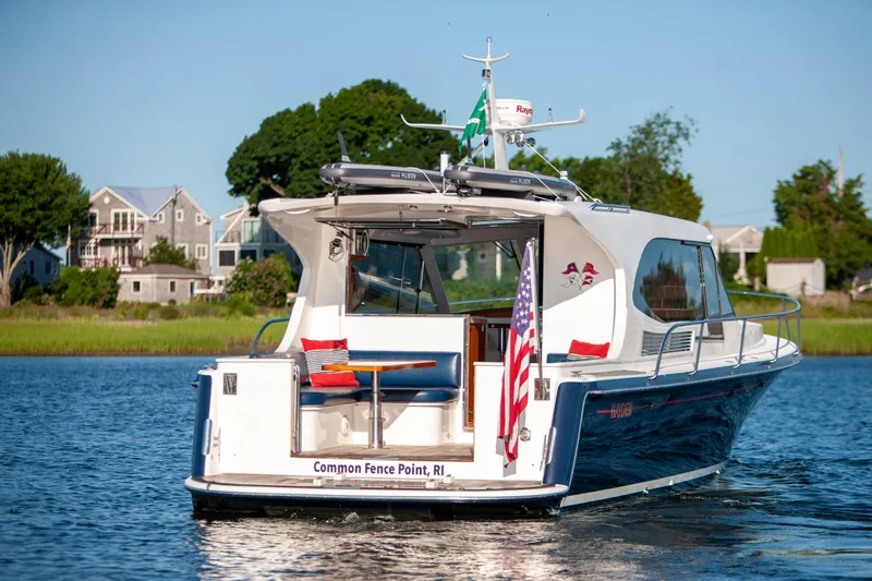  Yacht Photos Pics 2018 Hylas M44 yacht on water, American flag, coastal homes in background.