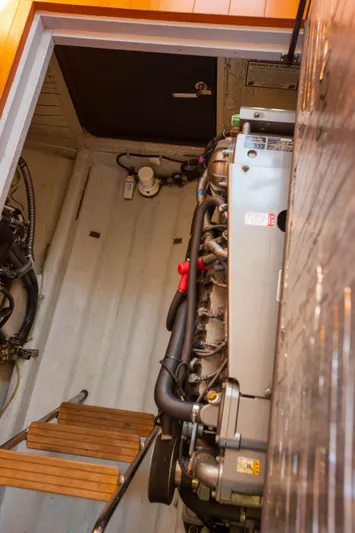  Yacht Photos Pics Engine room of a 2018 Hylas M44 yacht, showcasing mechanical components and wooden steps.