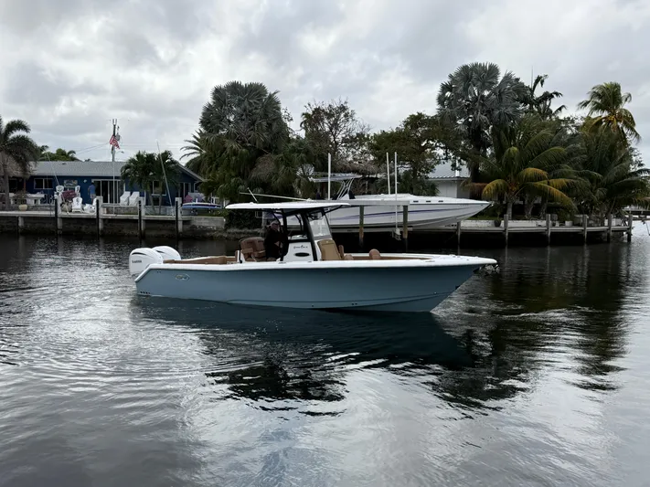  Yacht Photos Pics 2023 Sea Hunt Gamefish 30 boat on calm water near a dock with palm trees.