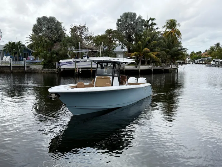  Yacht Photos Pics 2023 Sea Hunt Gamefish 30 boat on calm water, surrounded by tropical trees.