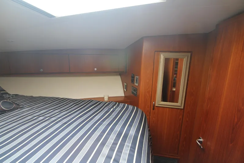 Pescador Yacht Photos Pics Interior cabin of 2013 Cabo 40 Hardtop Express with striped bedding and wooden paneling.
