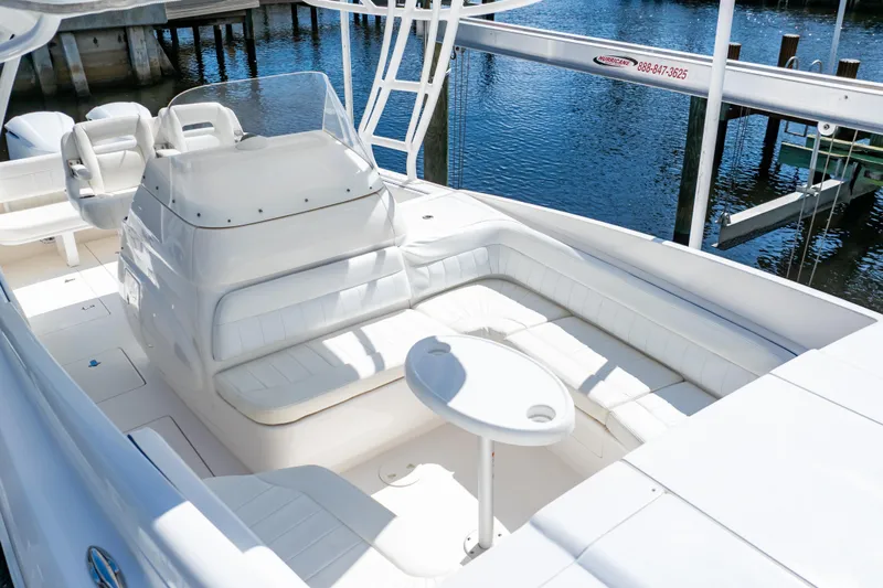  Yacht Photos Pics 2015 Intrepid 327 Cuddy boat interior with white seating and table, docked by the water.