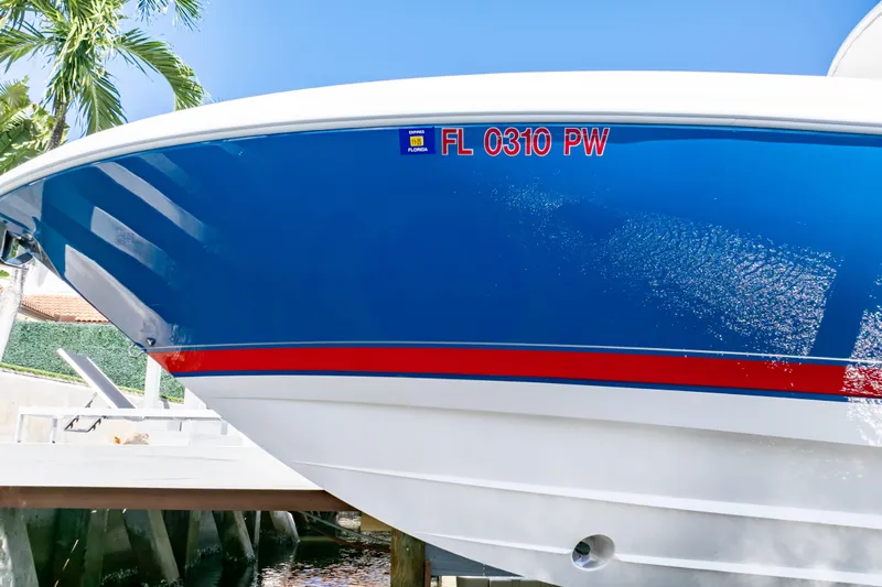  Yacht Photos Pics 2015 Intrepid 327 Cuddy boat with blue hull and red stripe, docked in sunny Florida.