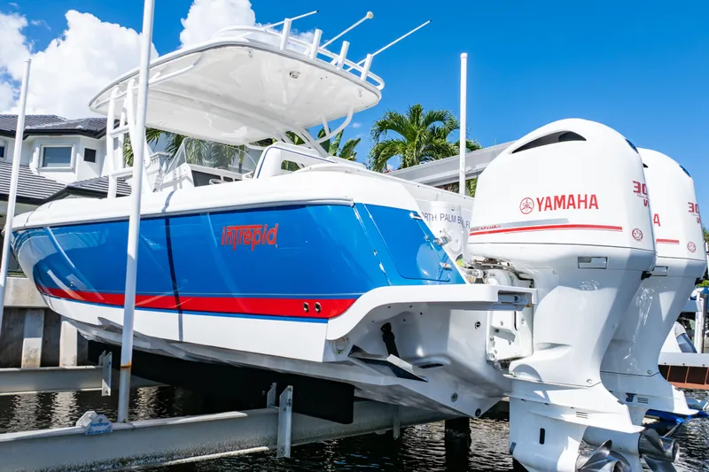  Yacht Photos Pics 2015 Intrepid 327 Cuddy boat with Yamaha engines on a lift, under a clear blue sky.