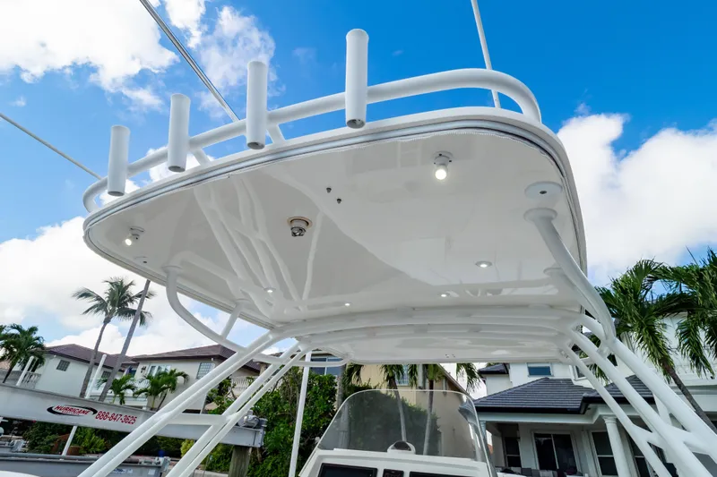  Yacht Photos Pics 2015 Intrepid 327 Cuddy boat with white canopy and rod holders against blue sky.