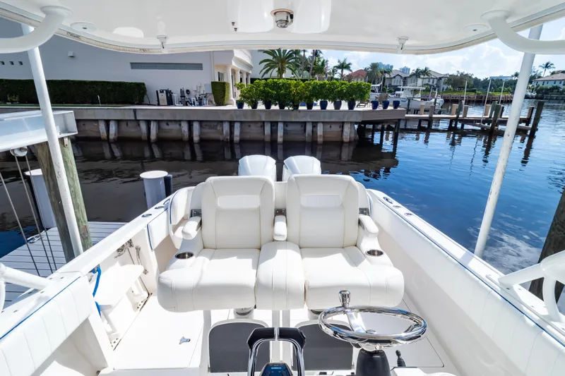  Yacht Photos Pics 2015 Intrepid 327 Cuddy boat interior with white seating and steering wheel, docked by waterfront homes.
