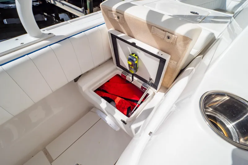  Yacht Photos Pics 2015 Intrepid 327 Cuddy boat storage compartment with safety equipment and red life jacket.