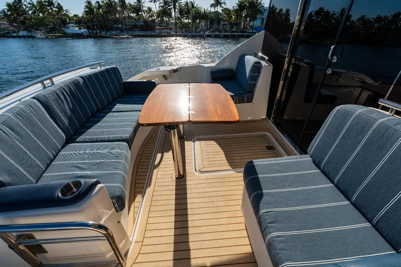 Down Time Yacht Photos Pics 2015 Tiara Yachts C44 Coupe deck with seating and table, overlooking water and palm trees.