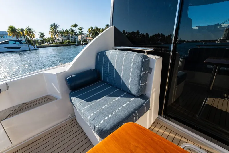 Down Time Yacht Photos Pics 2015 Tiara Yachts C44 Coupe with blue-striped seating, docked by palm trees and water.