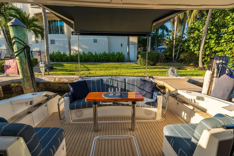 Down Time Yacht Photos Pics 2015 Tiara Yachts C44 Coupe cockpit with seating, table, and canopy in a marina setting.