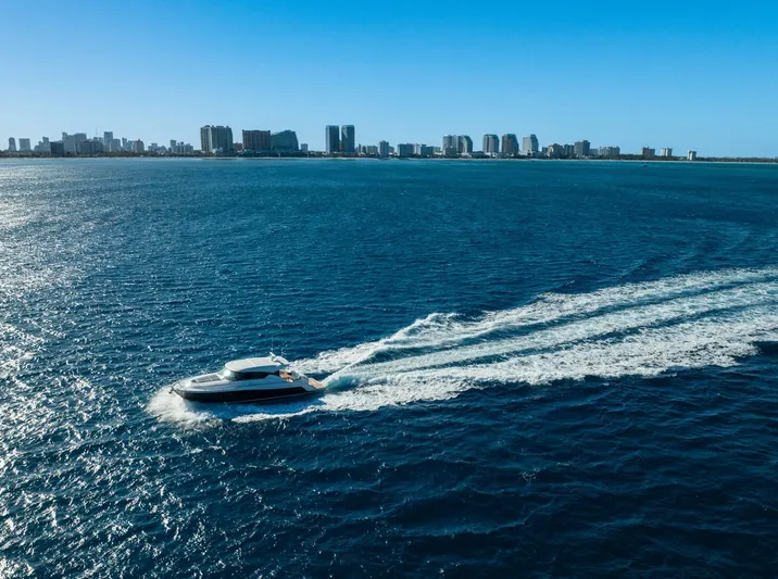 Down Time Yacht Photos Pics 2015 Tiara Yachts C44 Coupe cruising on blue ocean near city skyline.