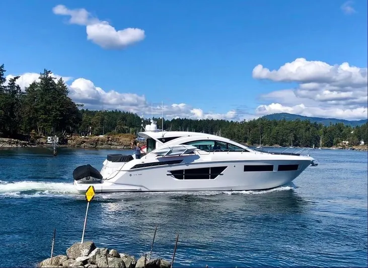  Yacht Photos Pics 2021 Cruisers Yachts 60 Cantius sailing on a scenic waterway under a clear blue sky.