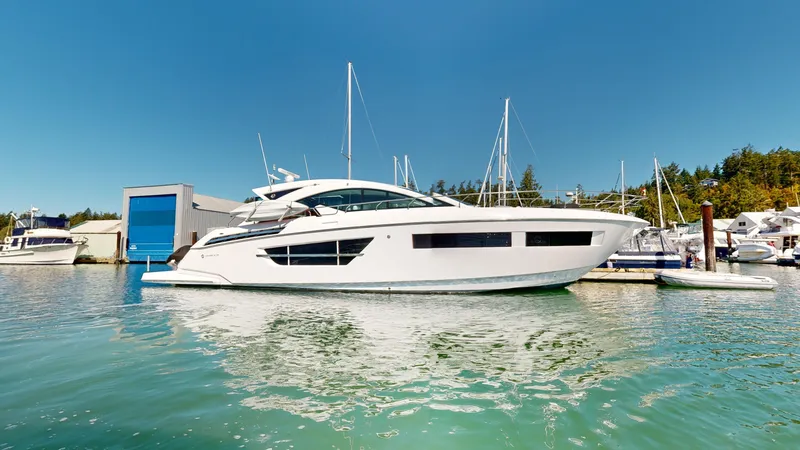  Yacht Photos Pics 2021 Cruisers Yachts 60 Cantius in marina, surrounded by boats and clear blue sky.