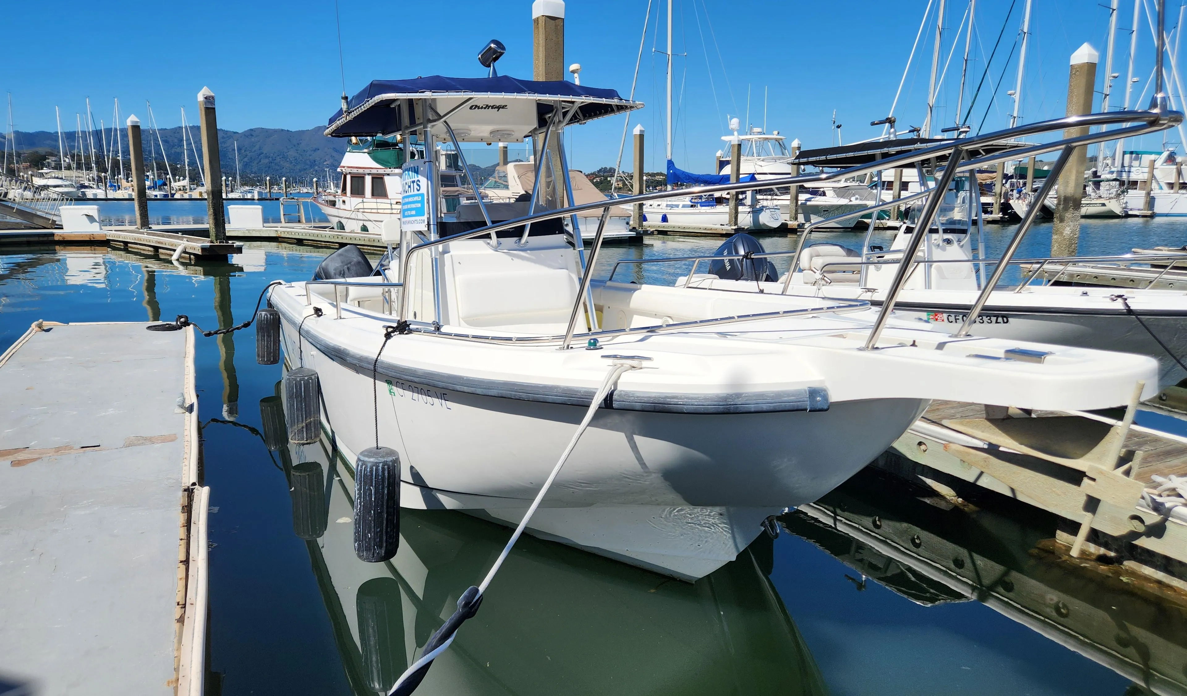 2001 Boston Whaler 26 Outrage boat docked in a marina under clear blue skies.