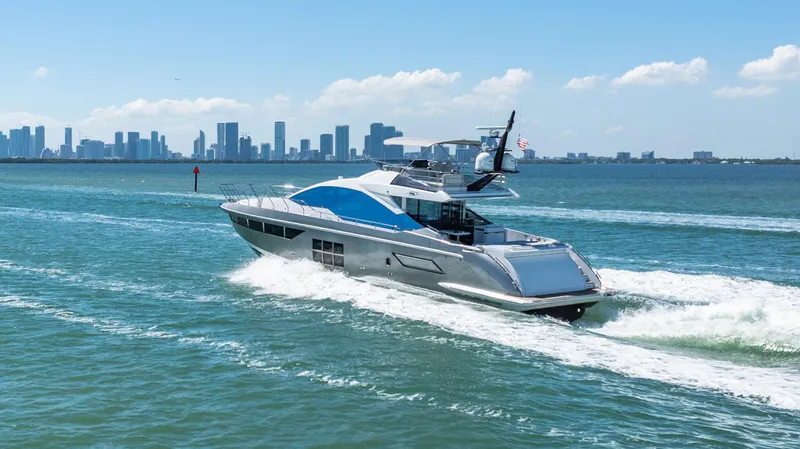 Swaha Yacht Photos Pics 2018 Azimut S7 yacht cruising on blue ocean with city skyline in background.