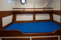 Wooden cabin interior with blue bedding on a 1929 Camper & Nicholsons J Class yacht.