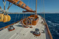 1929 Camper & Nicholsons J Class yacht sailing on open sea, showcasing wooden deck and helm.