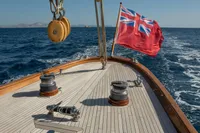 Deck of 1929 Camper & Nicholsons J Class yacht with British flag sailing on open sea.