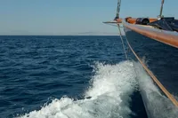 1929 Camper & Nicholsons J Class yacht sailing on open sea, creating waves.