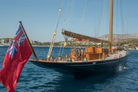 1929 Camper & Nicholsons J Class yacht sailing with a red ensign flag.