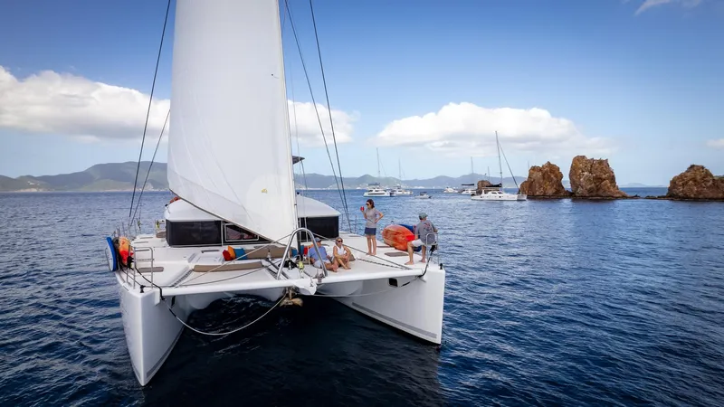 Copper Penny Yacht Photos Pics Lagoon 560 catamaran sailing in scenic waters, 2011 model, with rocky islands in the background.