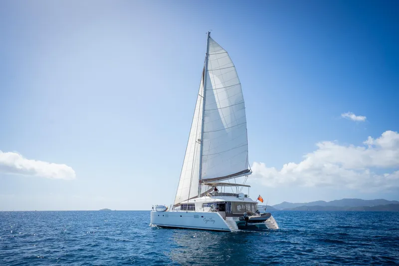 Copper Penny Yacht Photos Pics Sailing catamaran Lagoon 560, 2011 model, cruising on open sea under clear blue sky.