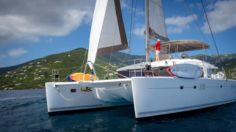 Copper Penny Yacht Photos Pics 2011 Lagoon 560 catamaran sailing near lush green hills under a clear blue sky.