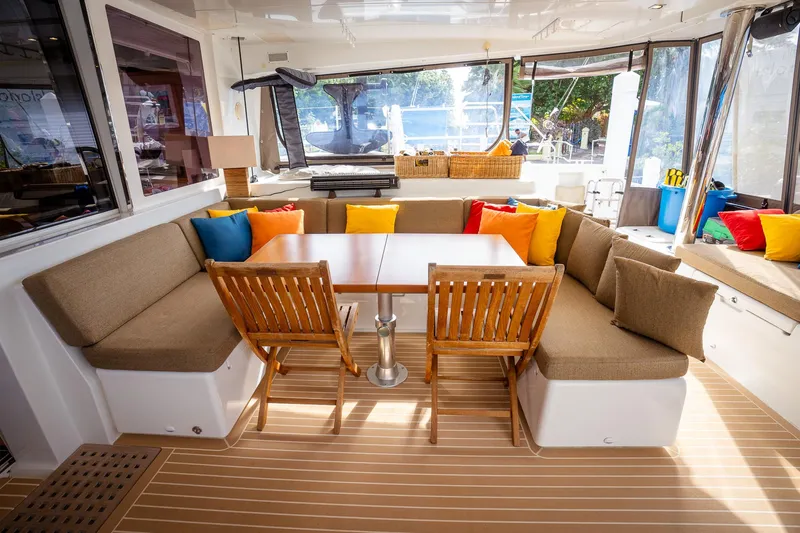 Copper Penny Yacht Photos Pics Luxurious Lagoon 560 yacht interior with cozy seating, colorful cushions, and wooden dining table.