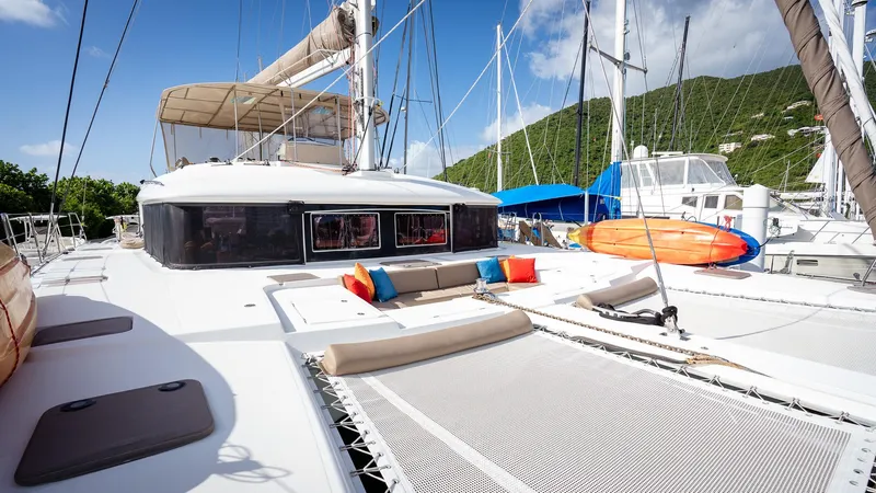 Copper Penny Yacht Photos Pics Lagoon 560 catamaran, 2011 model, with colorful cushions and paddleboards, docked in a marina.
