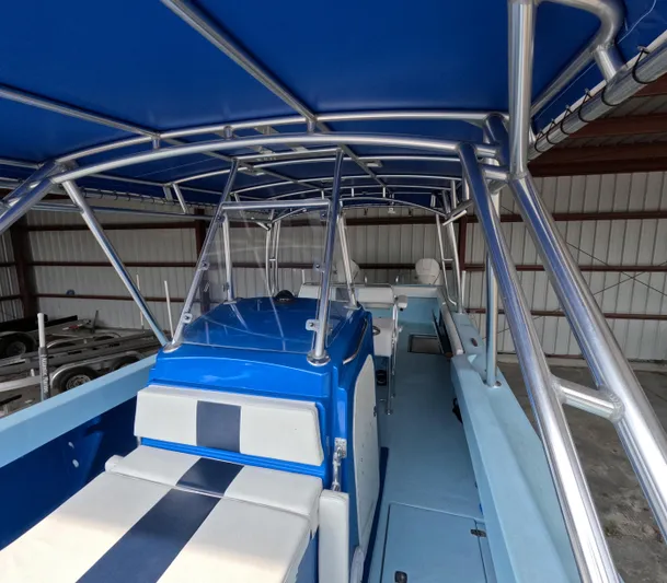 Cool Change Yacht Photos Pics 2022 Eastward 30 boat interior with blue and white seating, under a metal frame canopy.