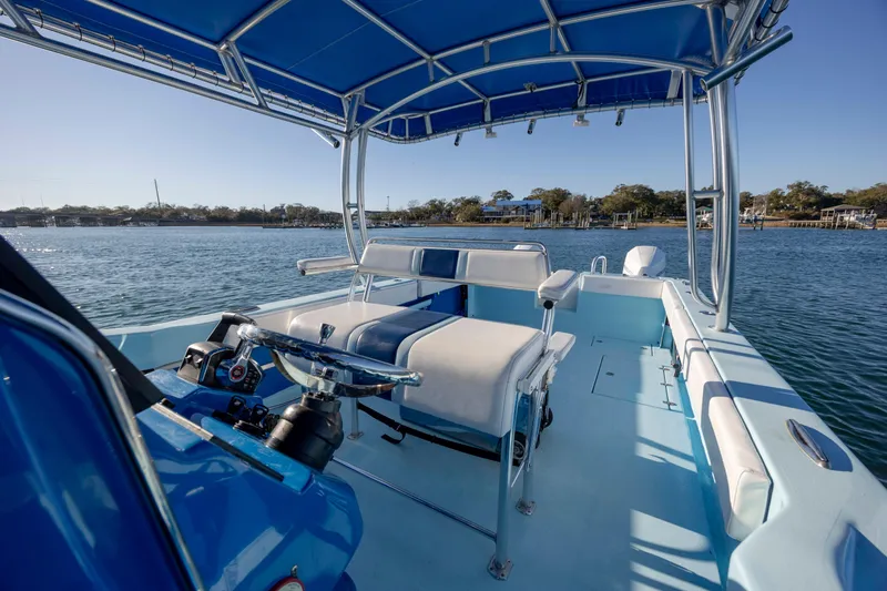 Cool Change Yacht Photos Pics 2022 Eastward 30 boat with blue canopy, steering wheel, and seating on calm water.