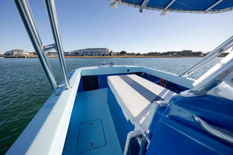 Cool Change Yacht Photos Pics 2022 Eastward 30 boat interior with blue seating, overlooking calm waters and distant buildings.